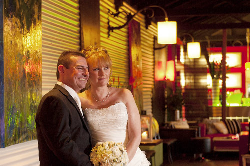 Wedding photography of newlyweds by the All Smiles venue feature wall.